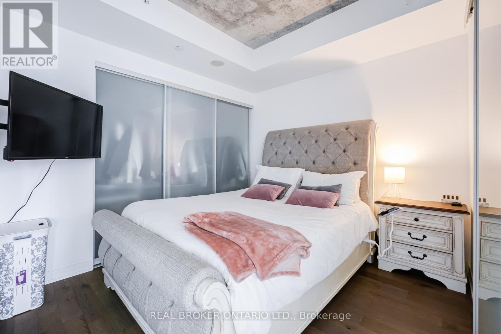 A bedroom with a bed, nightstand, and a television.