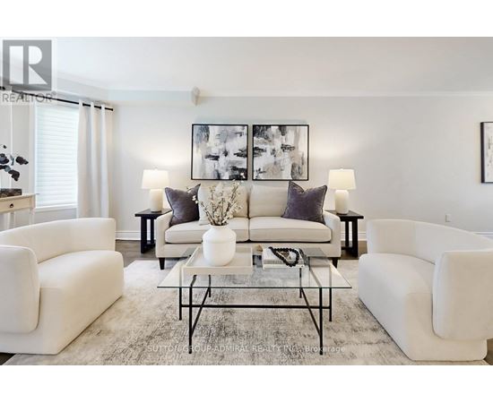 A living room with white furniture and a large painting on the wall.