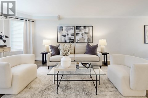 A living room with white furniture and a large painting on the wall.