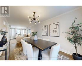 A dining room with a black table and white chairs.