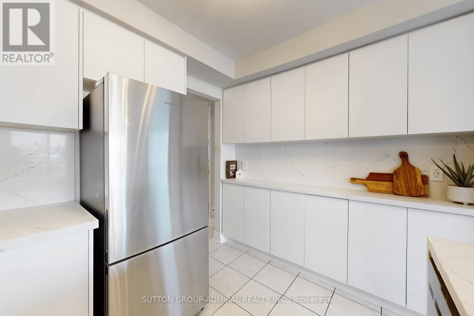 A kitchen with white cabinets and a stainless steel refrigerator.