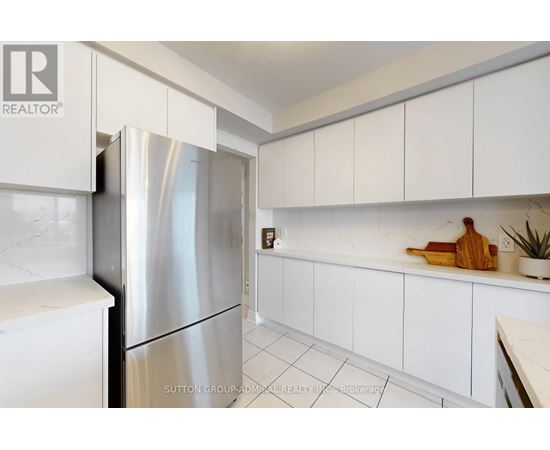 A kitchen with white cabinets and a stainless steel refrigerator.