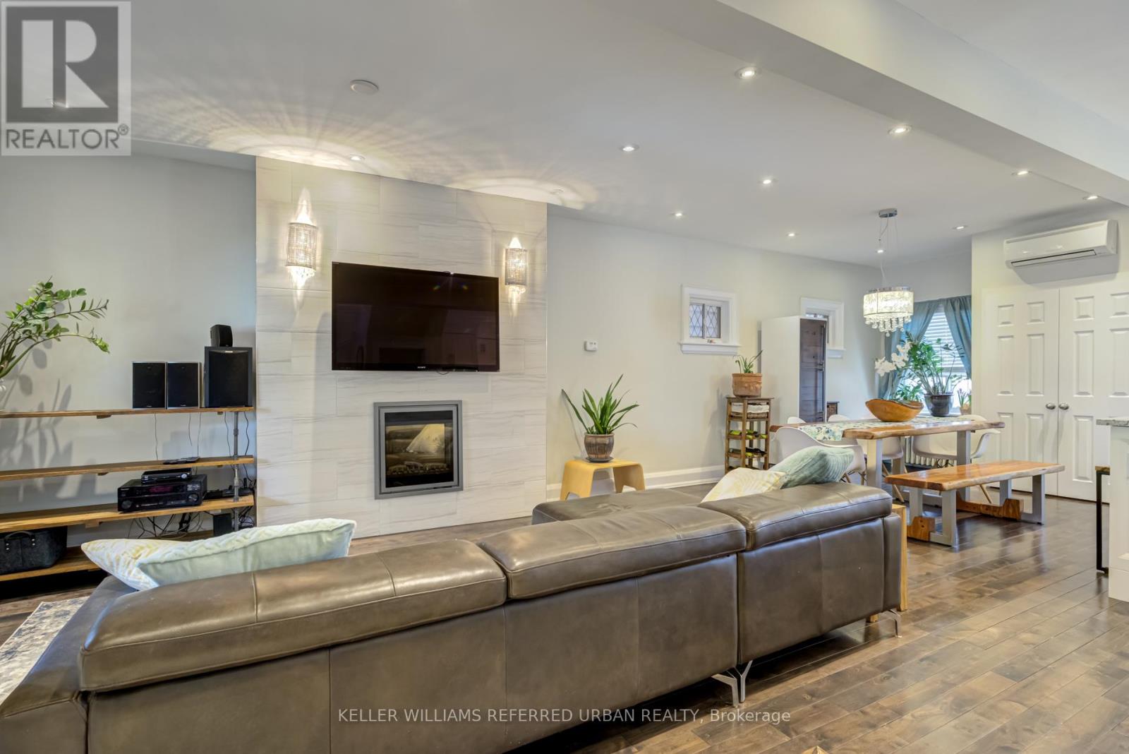 A modern living room with a large couch and a flat screen TV mounted on the wall.