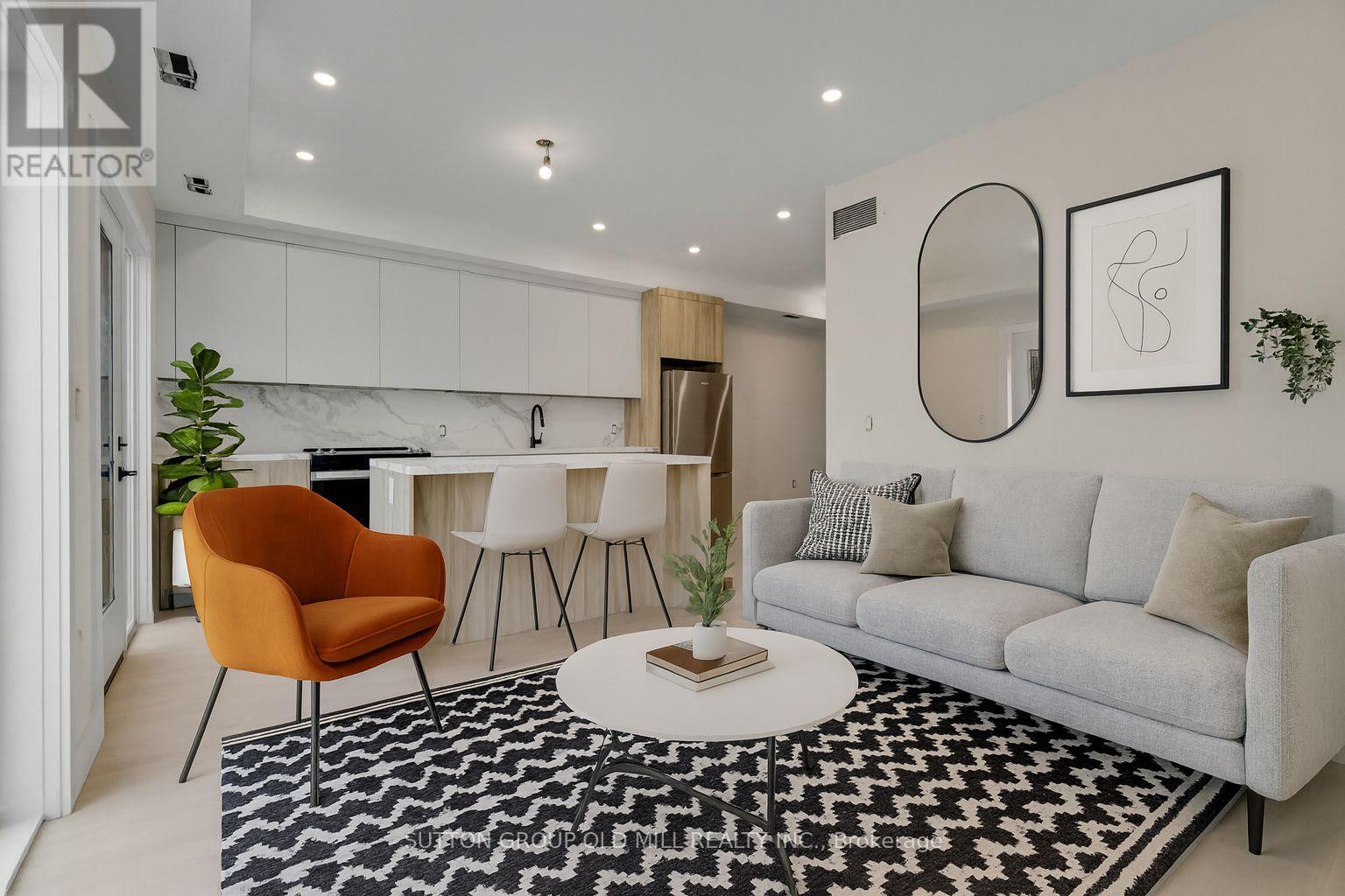 A living room with a grey couch, a round orange chair, and a black and white rug.