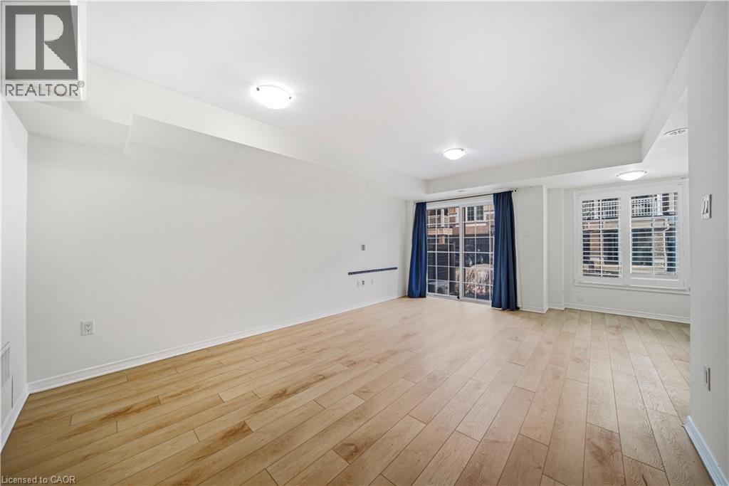A spacious room with wooden flooring and a window with blue curtains.
