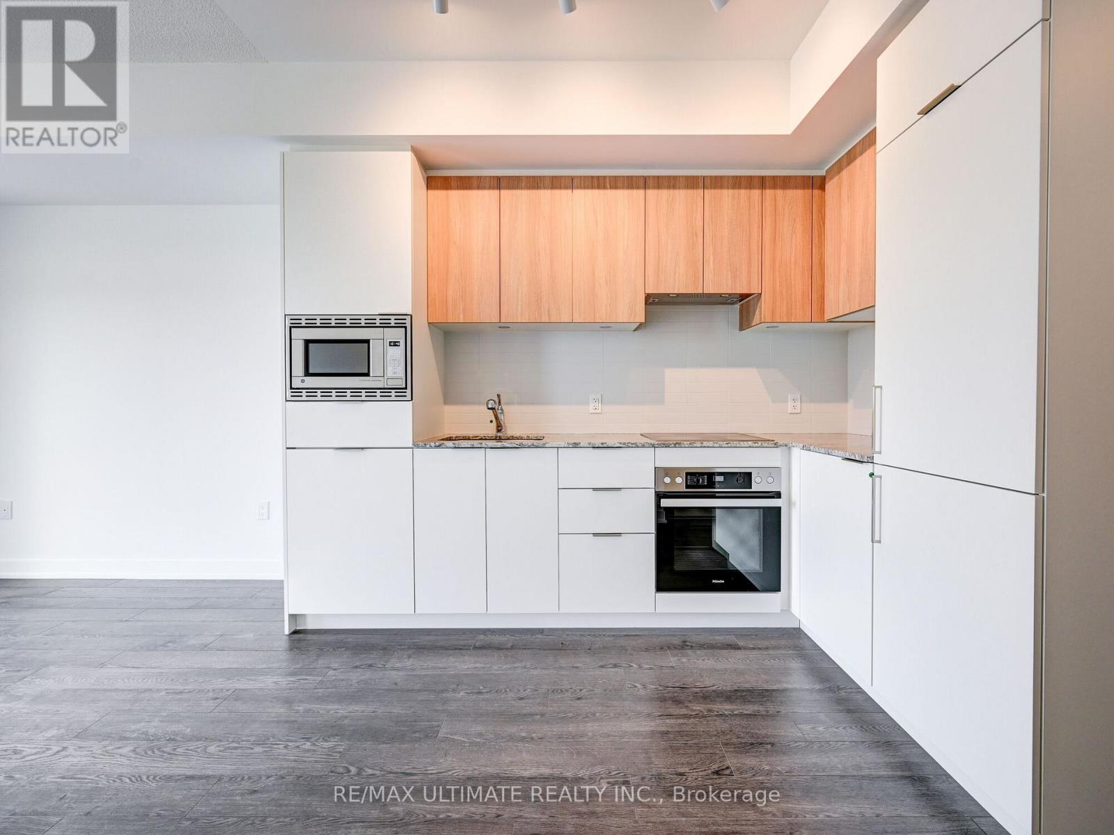 A kitchen with white cabinets and a microwave above the oven.