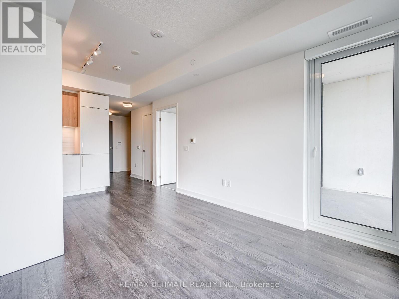 A spacious room with white walls and wooden flooring.
