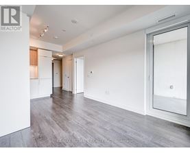 A spacious room with white walls and wooden flooring.
