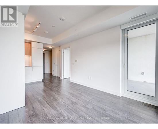 A spacious room with white walls and wooden flooring.