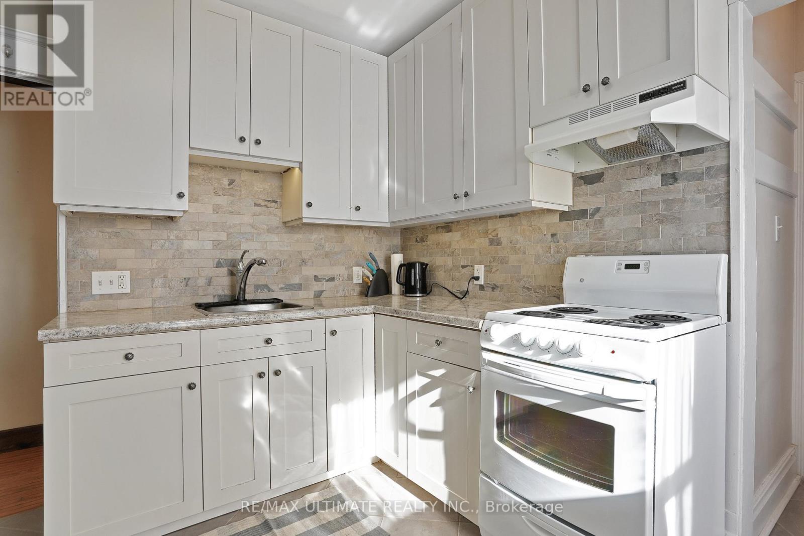 A kitchen with white cabinets and a white stove top oven.