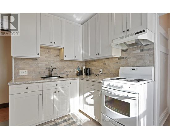 A kitchen with white cabinets and a white stove top oven.