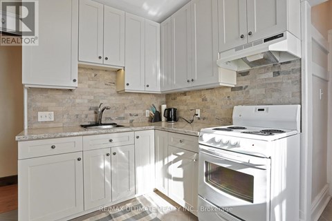 A kitchen with white cabinets and a white stove top oven.