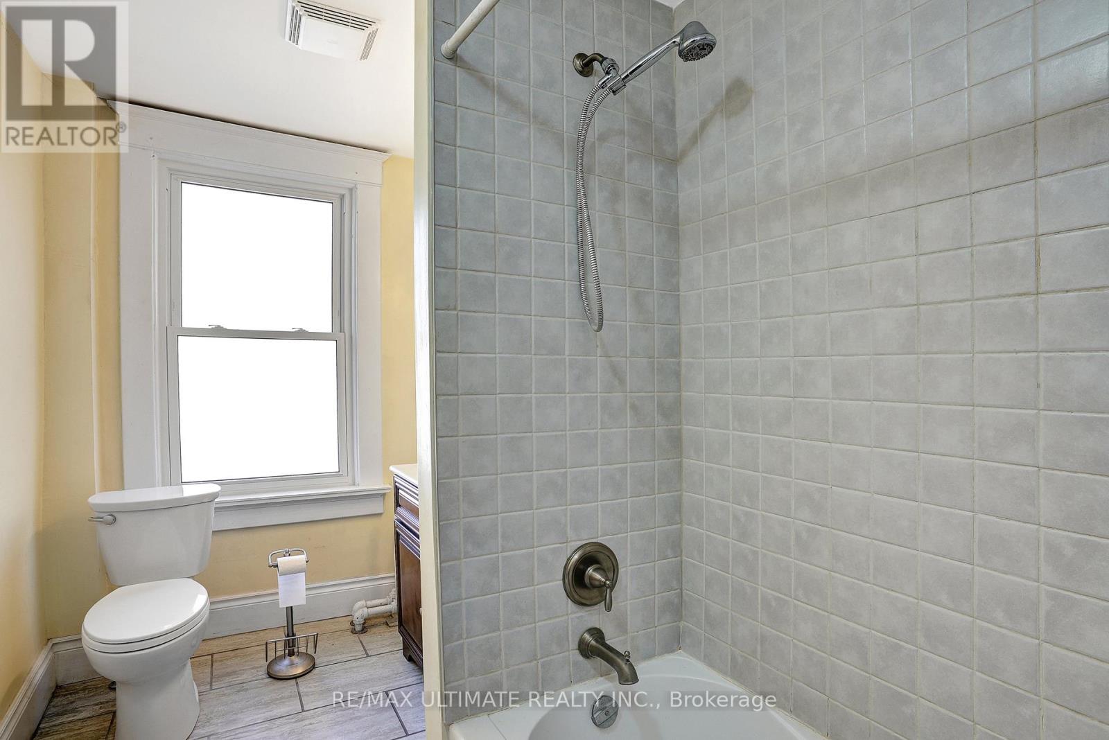 A bathroom with a toilet, a window, and a shower.