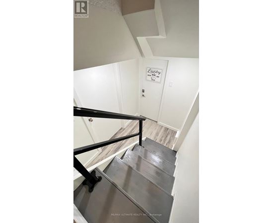 A staircase with a metal railing and a sign that says Laundry.