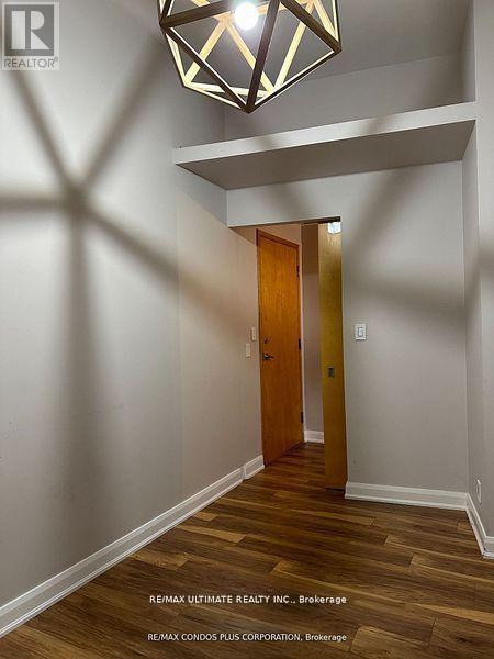 A hallway with a wooden floor and a light hanging from the ceiling.
