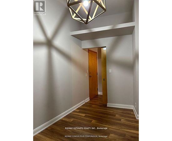 A hallway with a wooden floor and a light hanging from the ceiling.