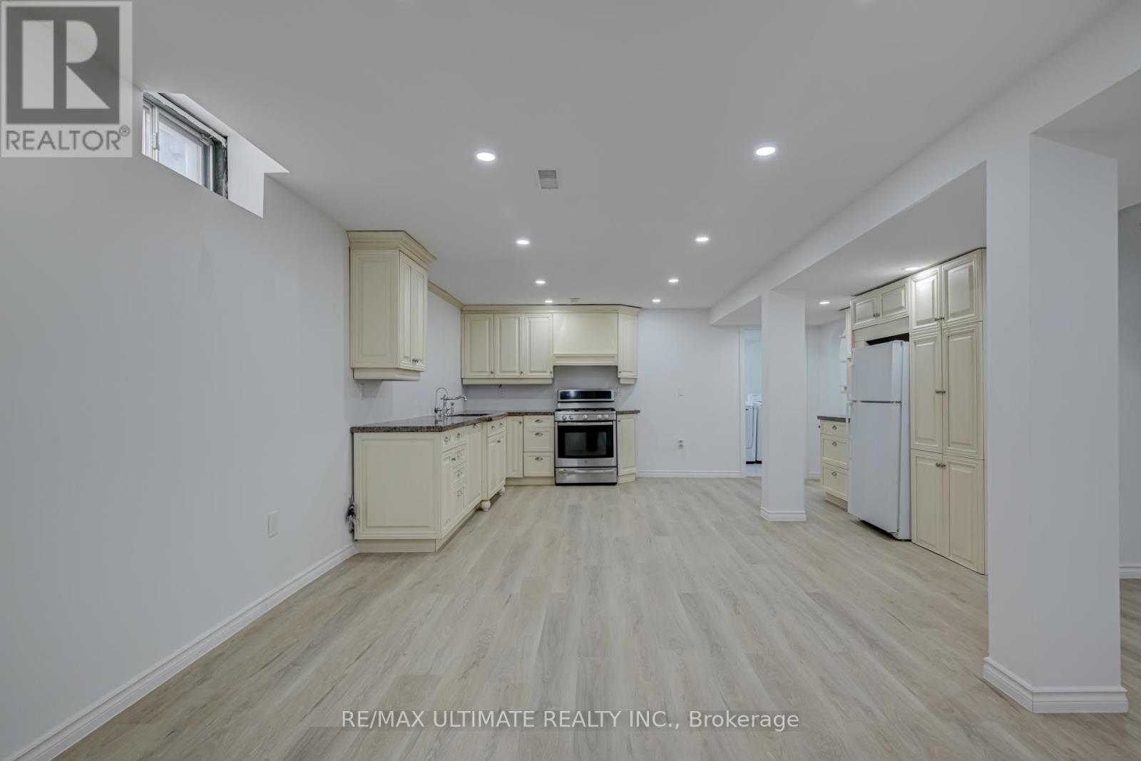 A spacious kitchen with white cabinets and a wooden floor.