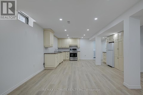 A spacious kitchen with white cabinets and a wooden floor.
