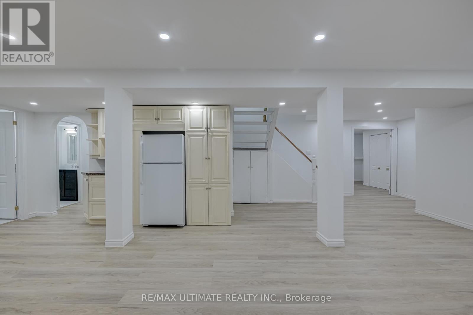 A spacious room with a white door and a staircase in the background.