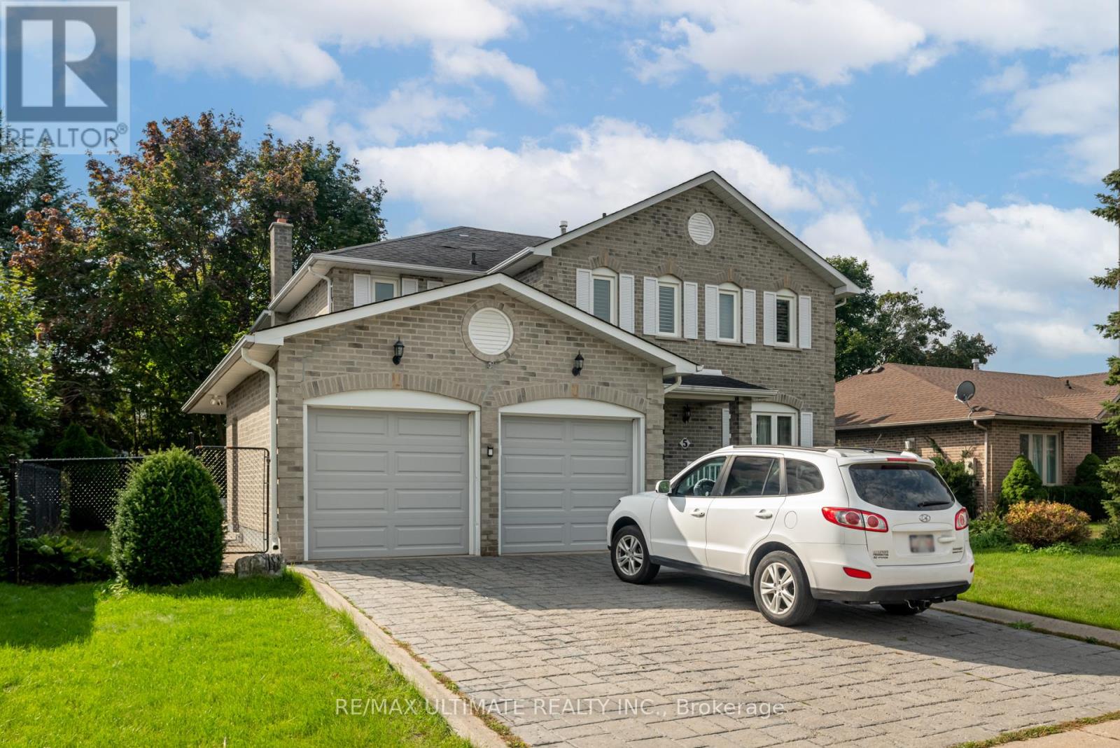 A white car is parked in front of a two-story house.