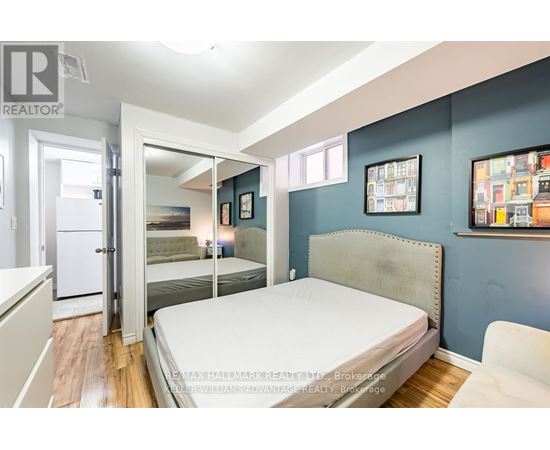 A bedroom with a bed, a chair, and pictures on the wall.