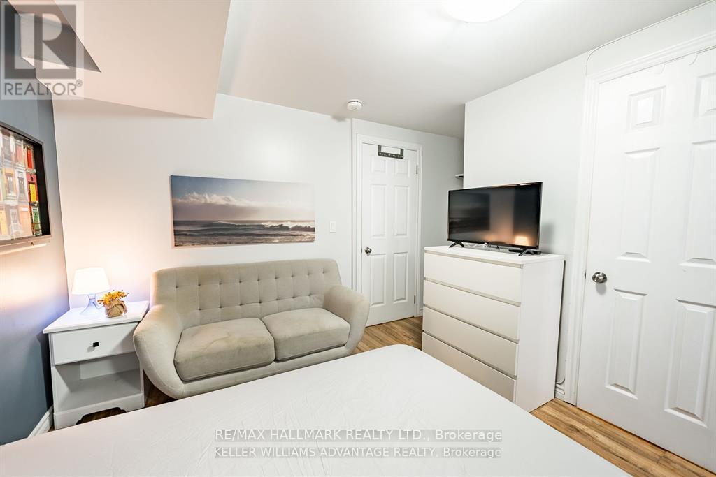 A well-lit bedroom with a beige sofa, a bed, and a television.