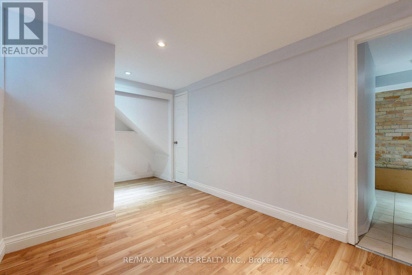 A room with wooden flooring and white walls, with a doorway leading to another room.