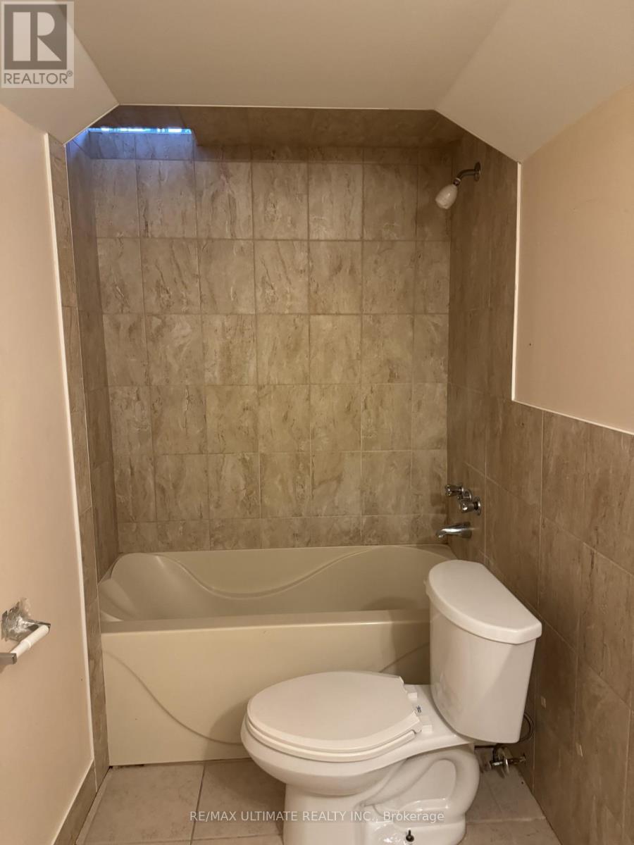 A white toilet is in a bathroom with a tiled shower area.
