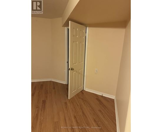 A white door is open in a room with wood flooring.