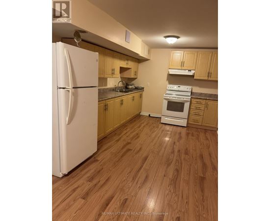 A kitchen with a white refrigerator and wooden cabinets.