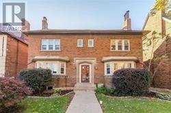 A brick house with a front yard and a walkway leading to the front door.