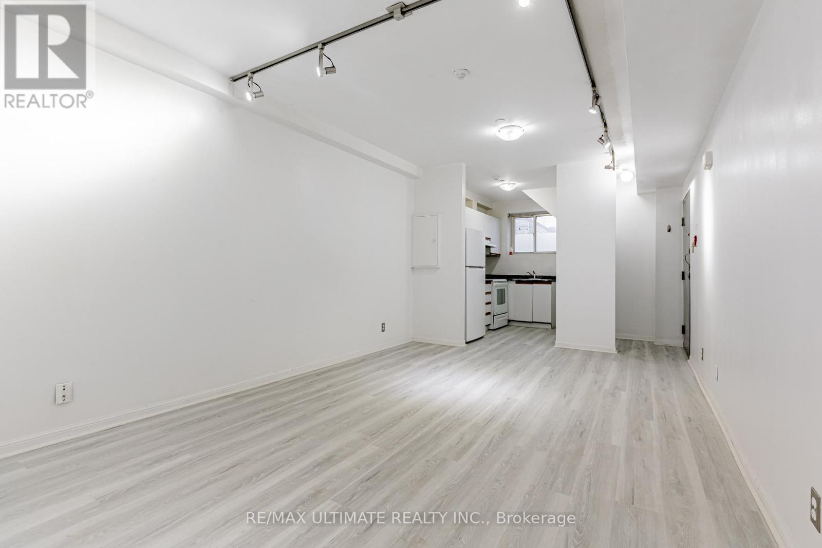 A spacious room with white walls and wooden flooring.