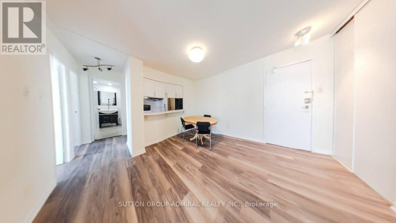 A spacious room with wooden flooring and white walls.