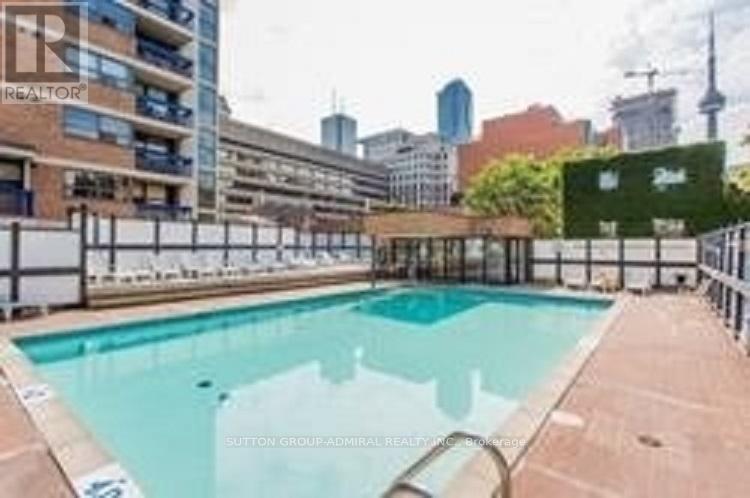 A swimming pool surrounded by a fence with a cityscape in the background.
