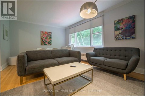 A living room with a grey couch, a coffee table, and a painting on the wall.
