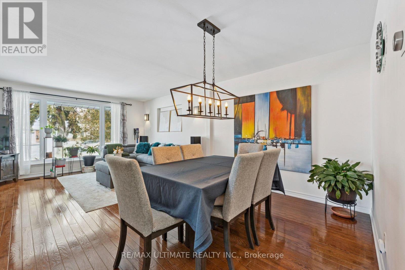 A dining room with a table set for four and a large painting on the wall.