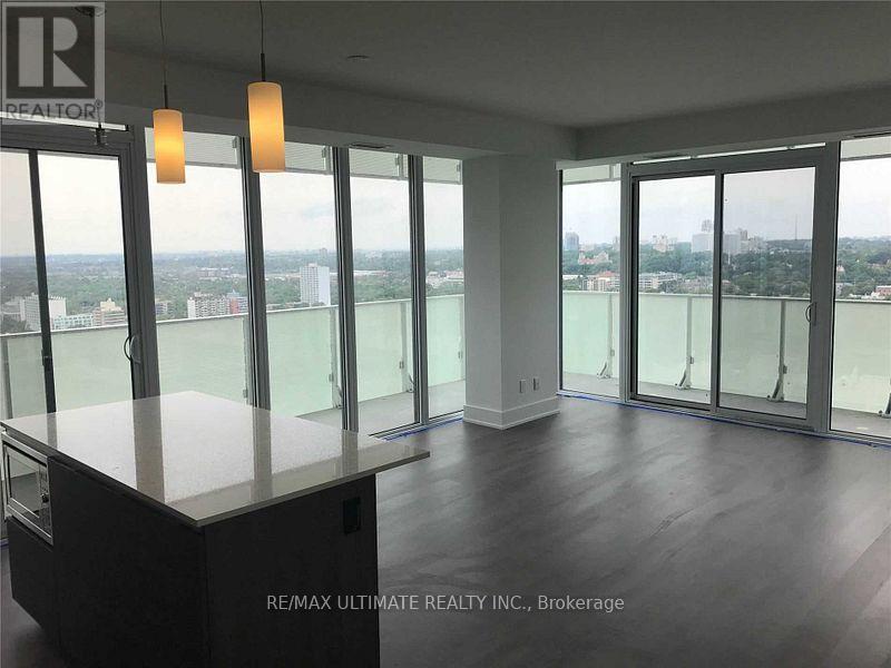 A spacious room with a view of the cityscape through large windows.