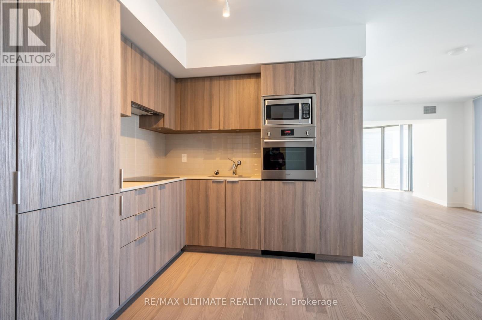 A modern kitchen with wooden cabinets and a microwave above the oven.