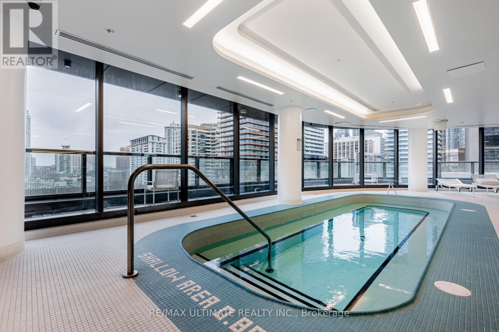 A swimming pool in a room with a glass wall.