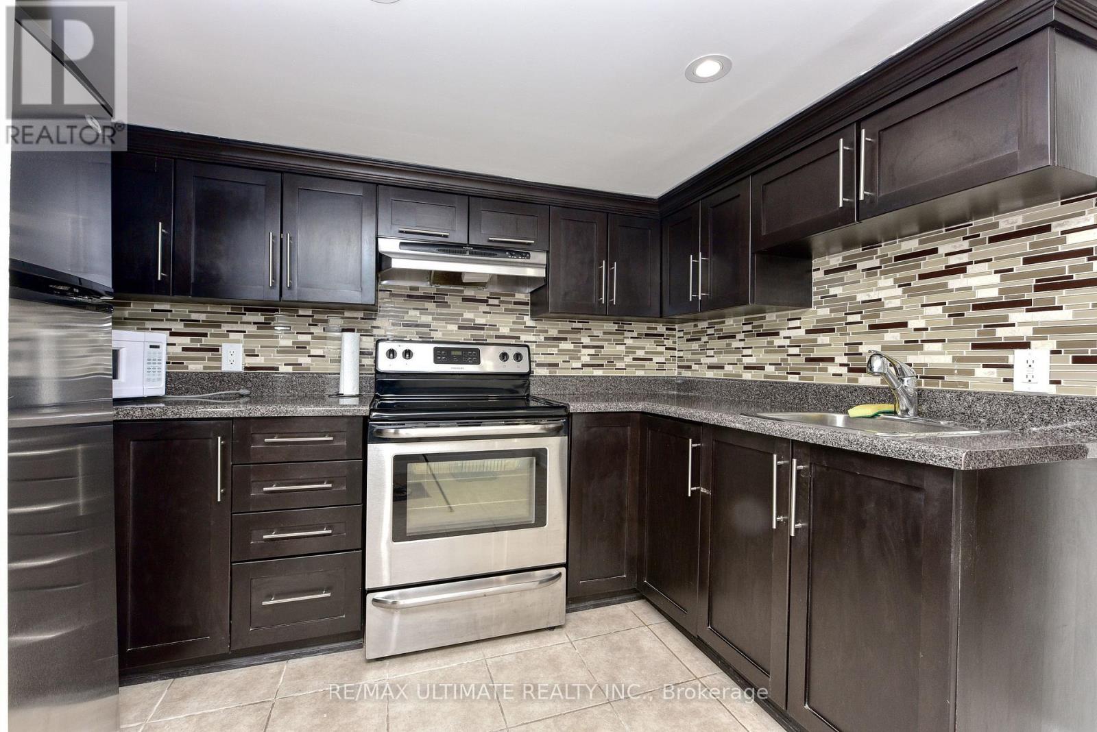 A kitchen with dark wood cabinets and a stone backsplash.