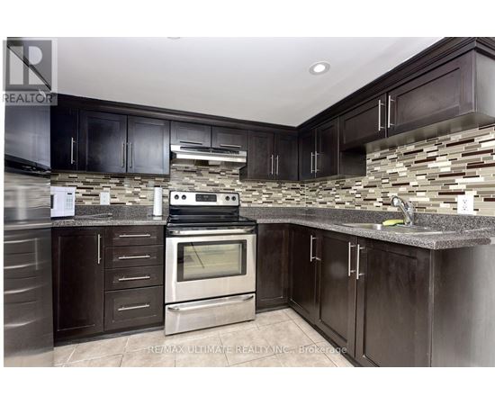 A kitchen with dark wood cabinets and a stone backsplash.