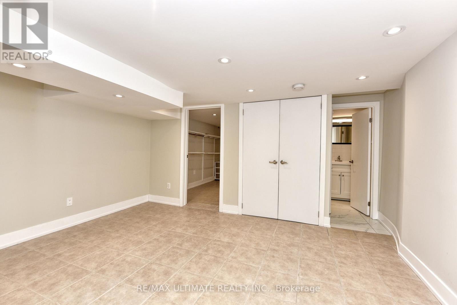 A spacious room with beige walls and carpeted floor, featuring a white door and a white cabinet.