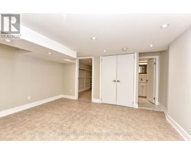 A spacious room with beige walls and carpeted floor, featuring a white door and a white cabinet.