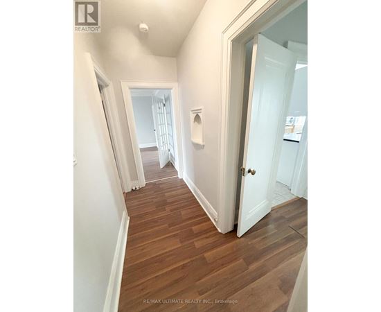 A hallway with wood floors and white walls.