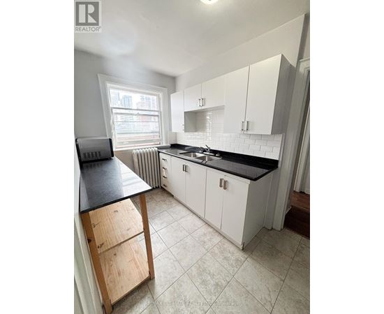 A kitchen with white cabinets and a black countertop.