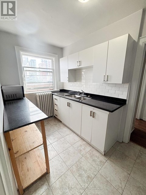 A kitchen with white cabinets and a black countertop.