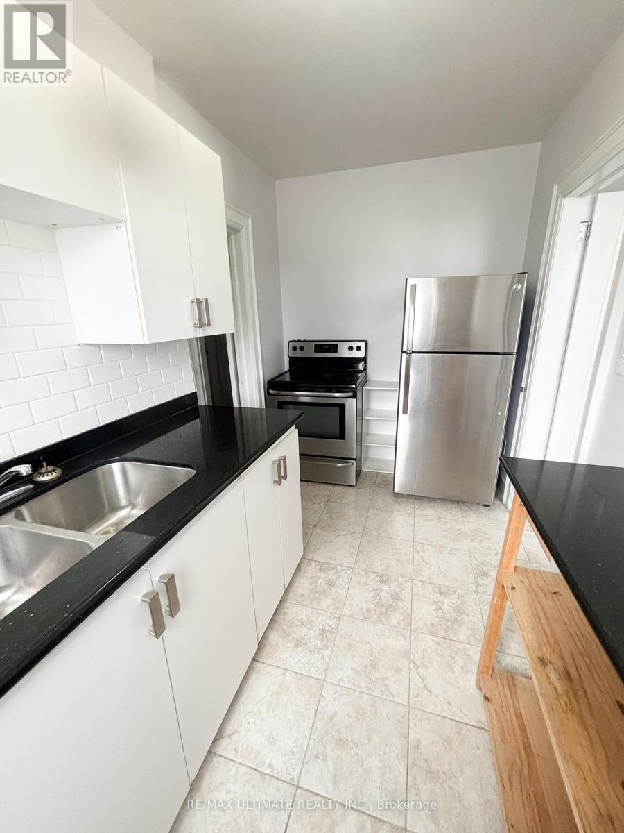 A kitchen with white cabinets and black countertops.