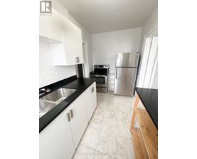 A kitchen with white cabinets and black countertops.