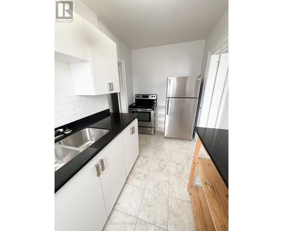 A kitchen with white cabinets and black countertops.