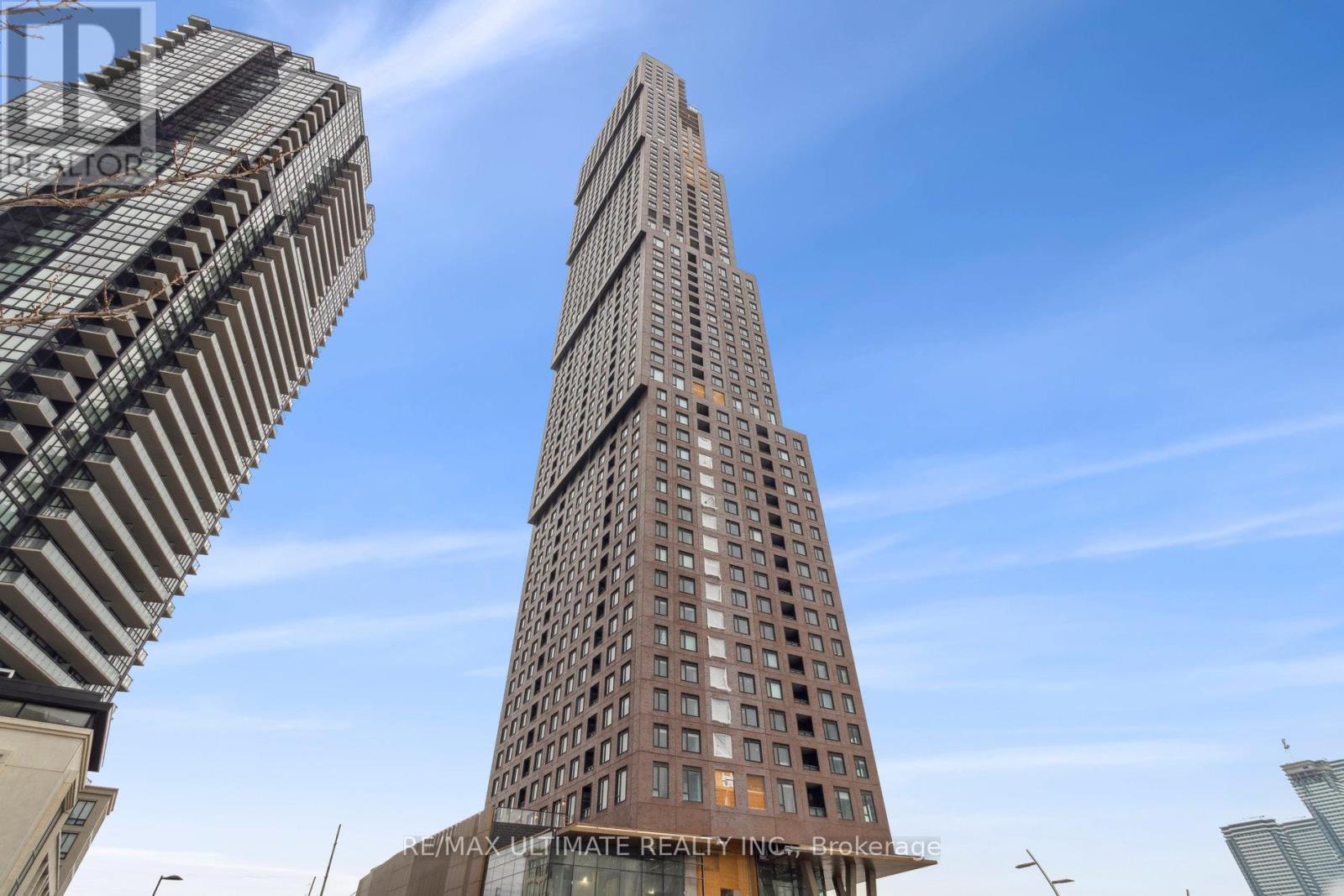 A tall building with a unique curved top stands next to a shorter, more traditional skyscraper.
